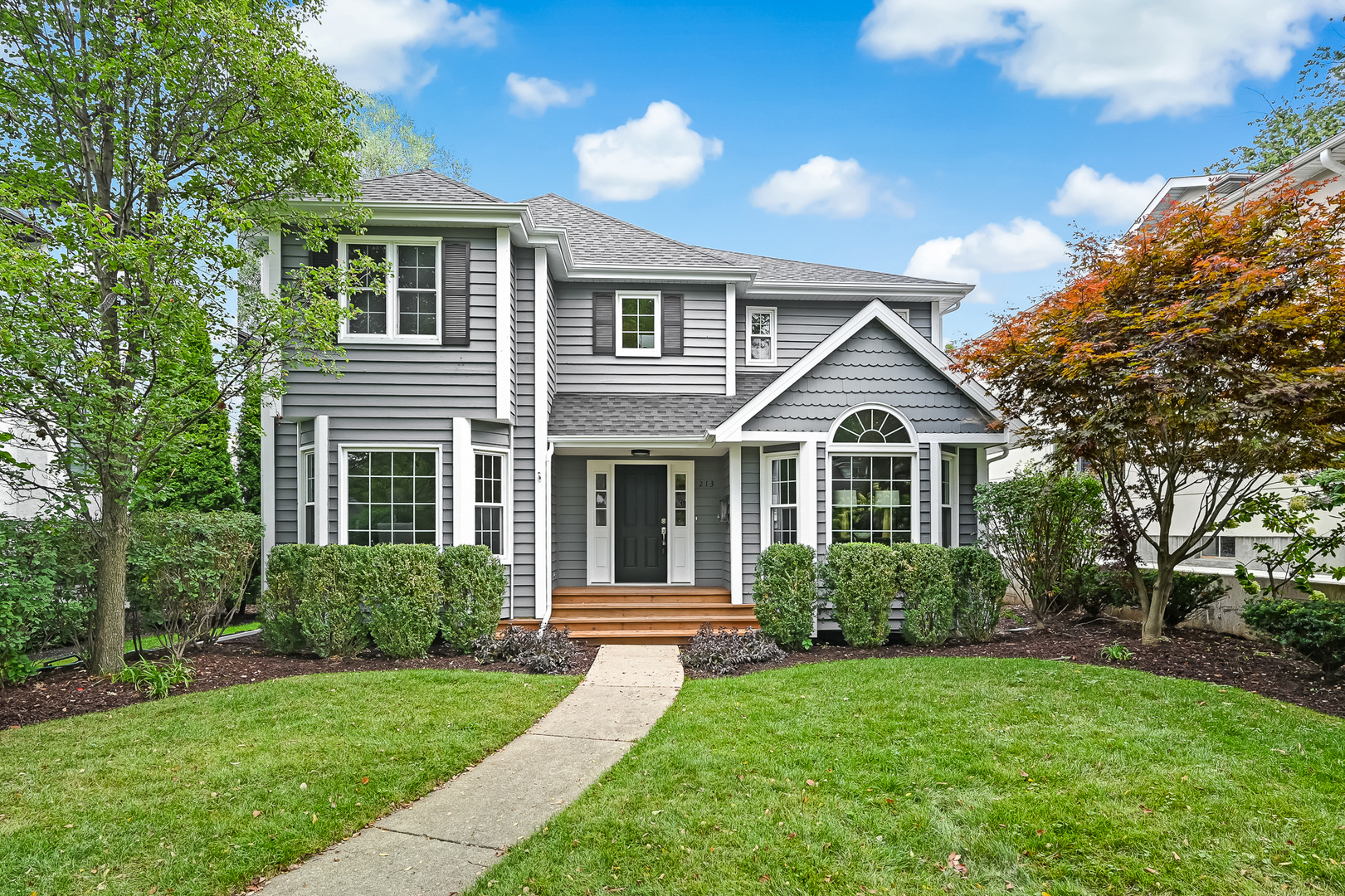 a front view of a house with a yard and trees