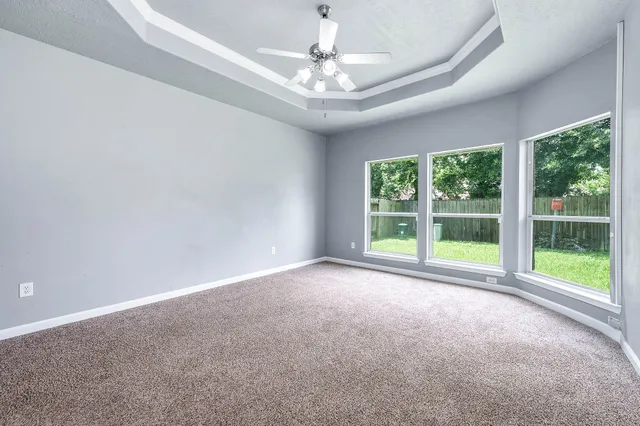 an empty room with windows and fan