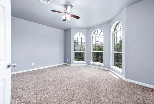 a view of a livingroom with wooden floor a ceiling fan and window