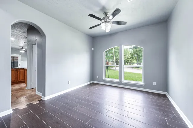 a view of an empty room with a window and wooden floor