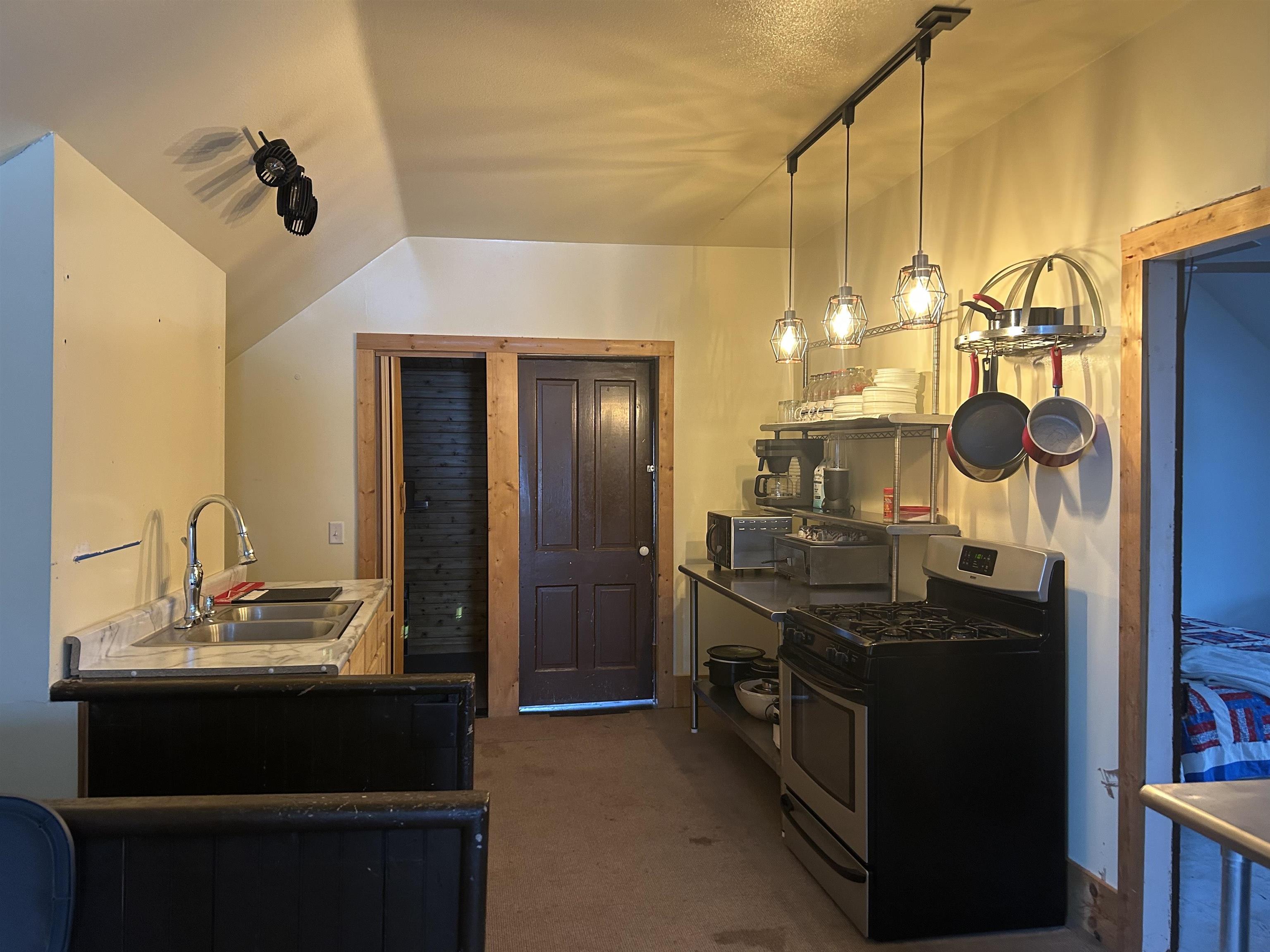 59460 Main Street Mason, WI 54856 - Photo 5 of 18 Kitchen featuring lofted ceiling, sink, hanging light fixtures, dark carpet, and gas stove