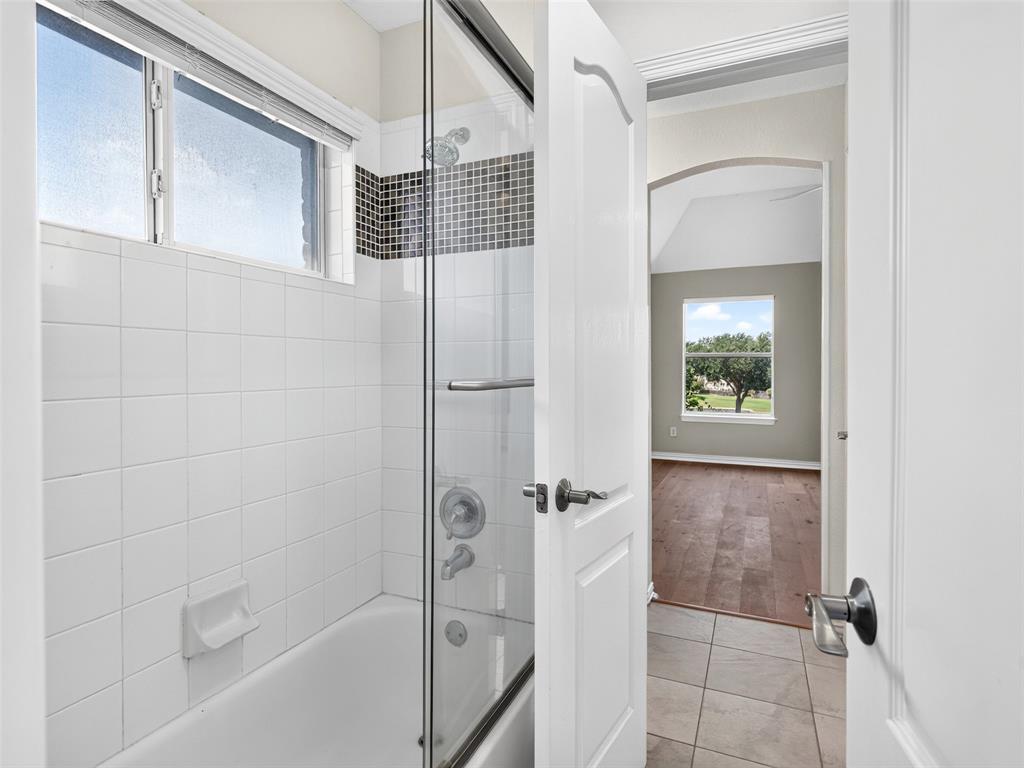 6809 Cedar Ridge Court Plano, TX 75093 - Photo 29 of 38 Tub/shower combination featuring a mosaic tile accent and glass enclosure