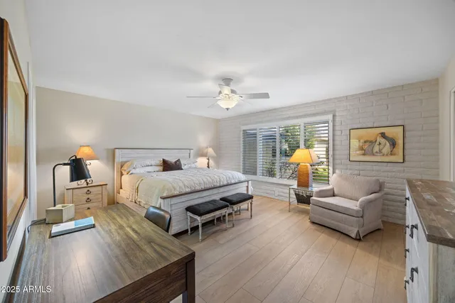 a spacious bedroom with a bed a couch and a dresser with wooden floor