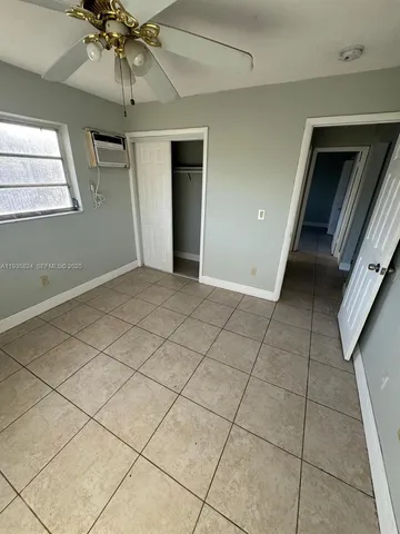 a view of an empty room and chandelier fan
