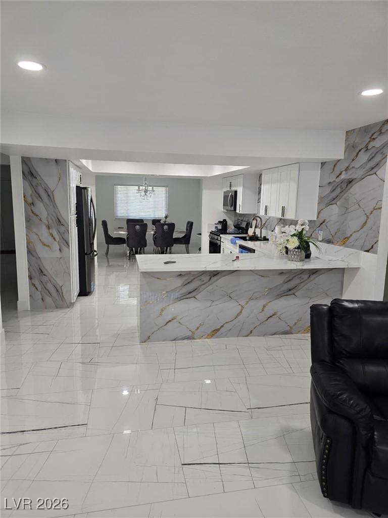 3153 Downing Place Las Vegas, NV 89121 - Photo 1 of 7 Kitchen featuring recessed lighting, light stone counters, a peninsula, white cabinetry, and stainless steel appliances