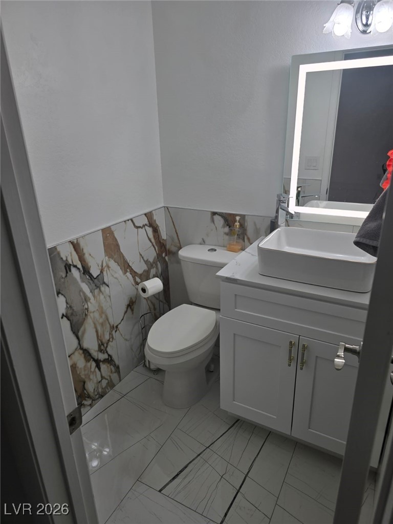 3153 Downing Place Las Vegas, NV 89121 - Photo 7 of 7 Bathroom featuring vanity, tile walls, light marble finish floors, a wainscoted wall, and a textured wall