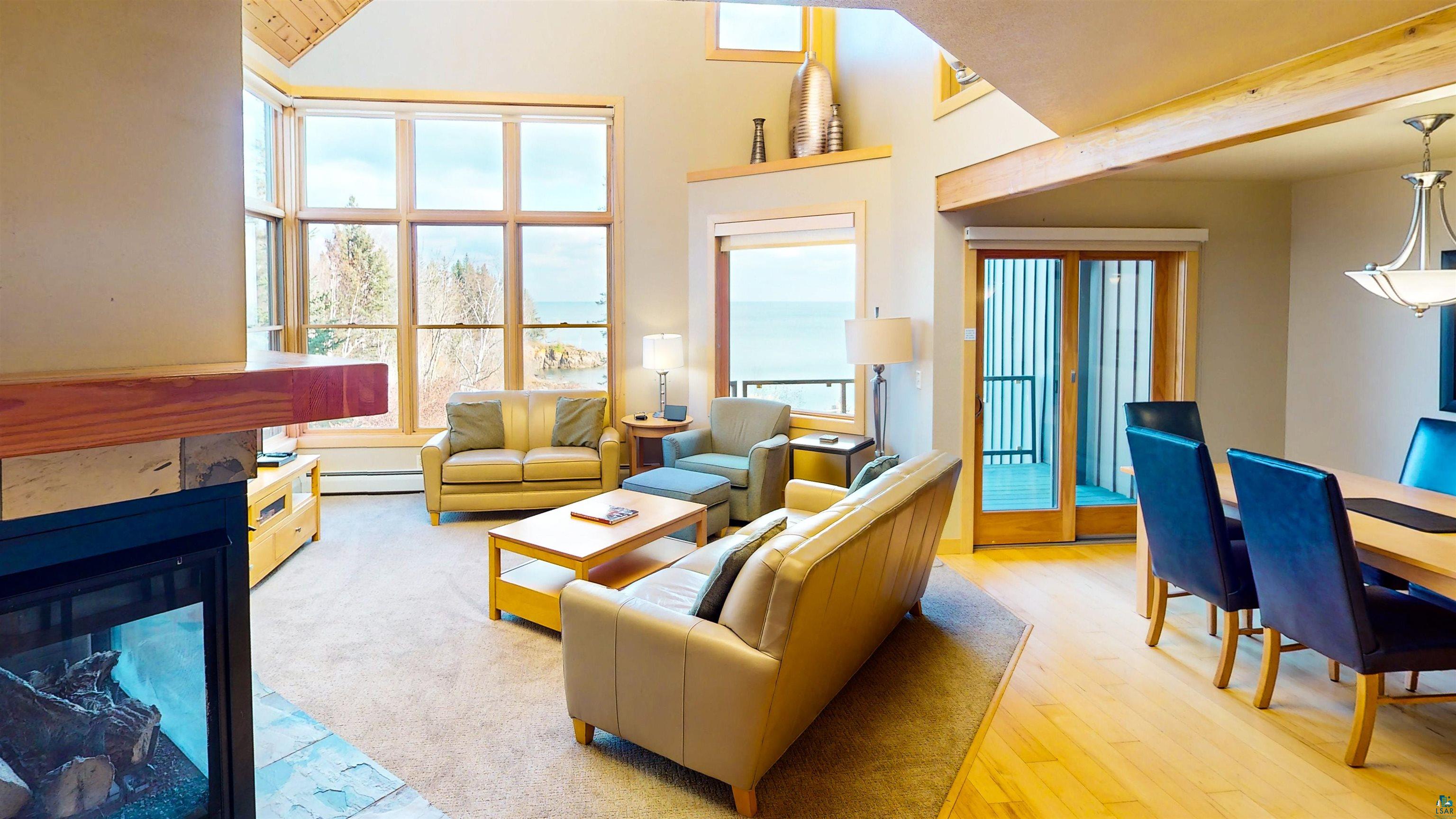 40 Surfside Drive, Unit 5D Tofte, MN 55615 - Photo 29 of 37 Living area featuring large multi-pane windows, a built-in fireplace with a stone hearth, vaulted wood-plank ceilings, and wood-finish flooring