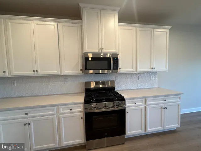 a kitchen with stainless steel appliances granite countertop white cabinets and a stove