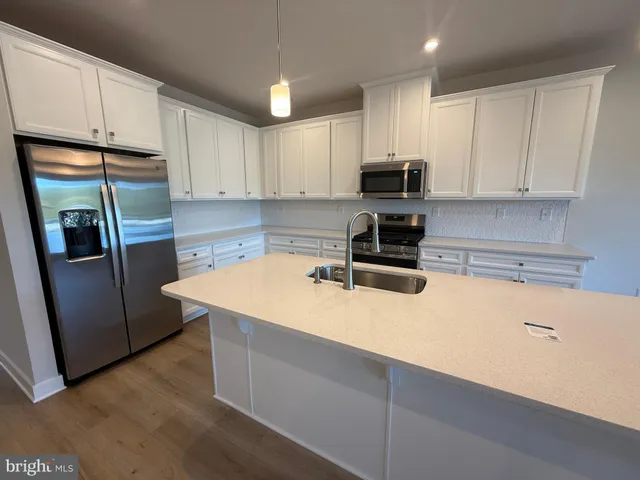 a kitchen with stainless steel appliances a refrigerator a sink a stove a microwave and cabinets