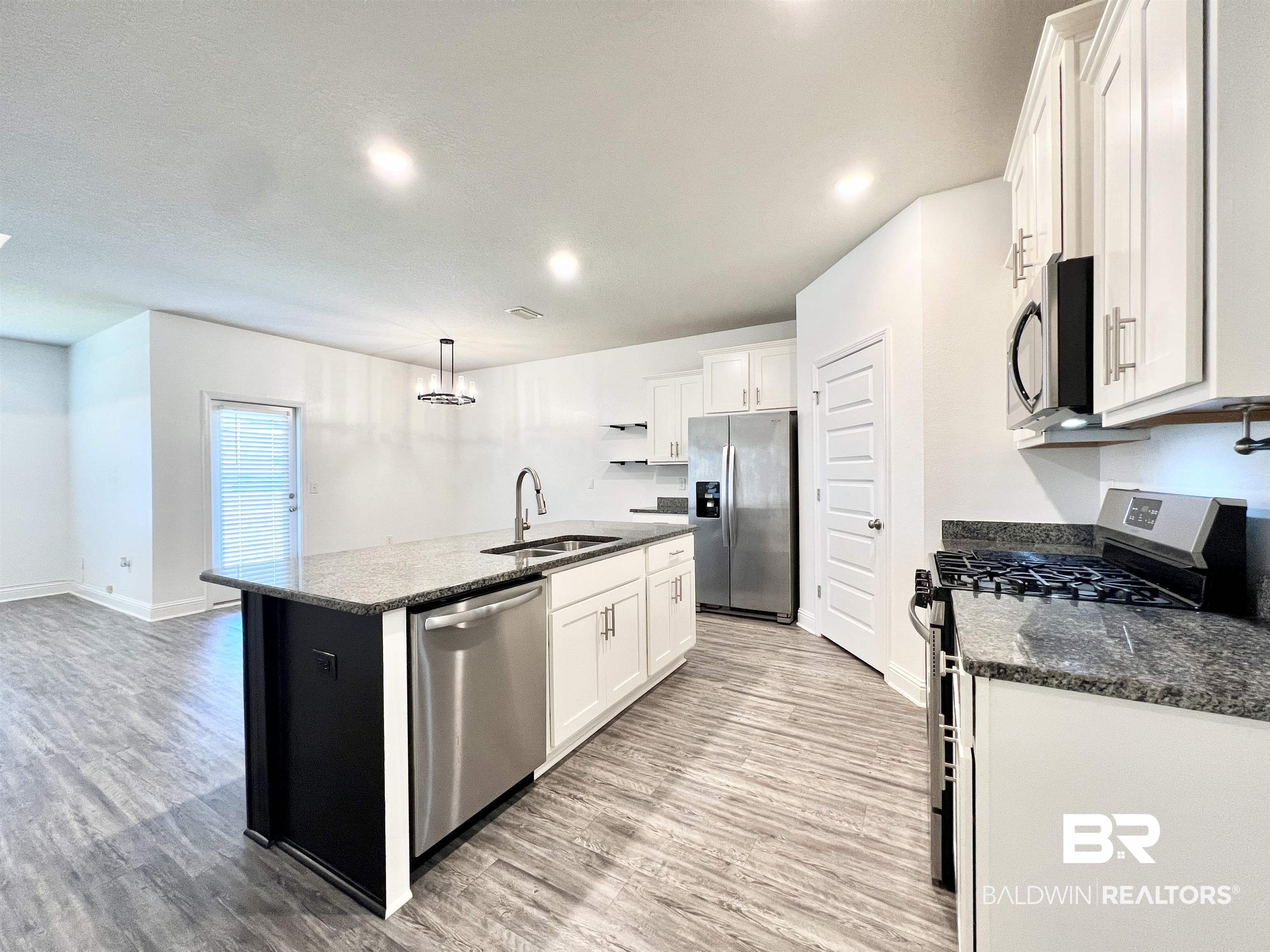 24785 Slater Mill Road Daphne, AL 36526 - Photo 3 of 46 Kitchen featuring an island with sink, hanging light fixtures, sink, white cabinetry, and appliances with stainless steel finishes