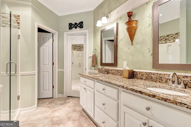a en suite bathroom with a granite countertop sink a mirror a glass door a shower and a mirror