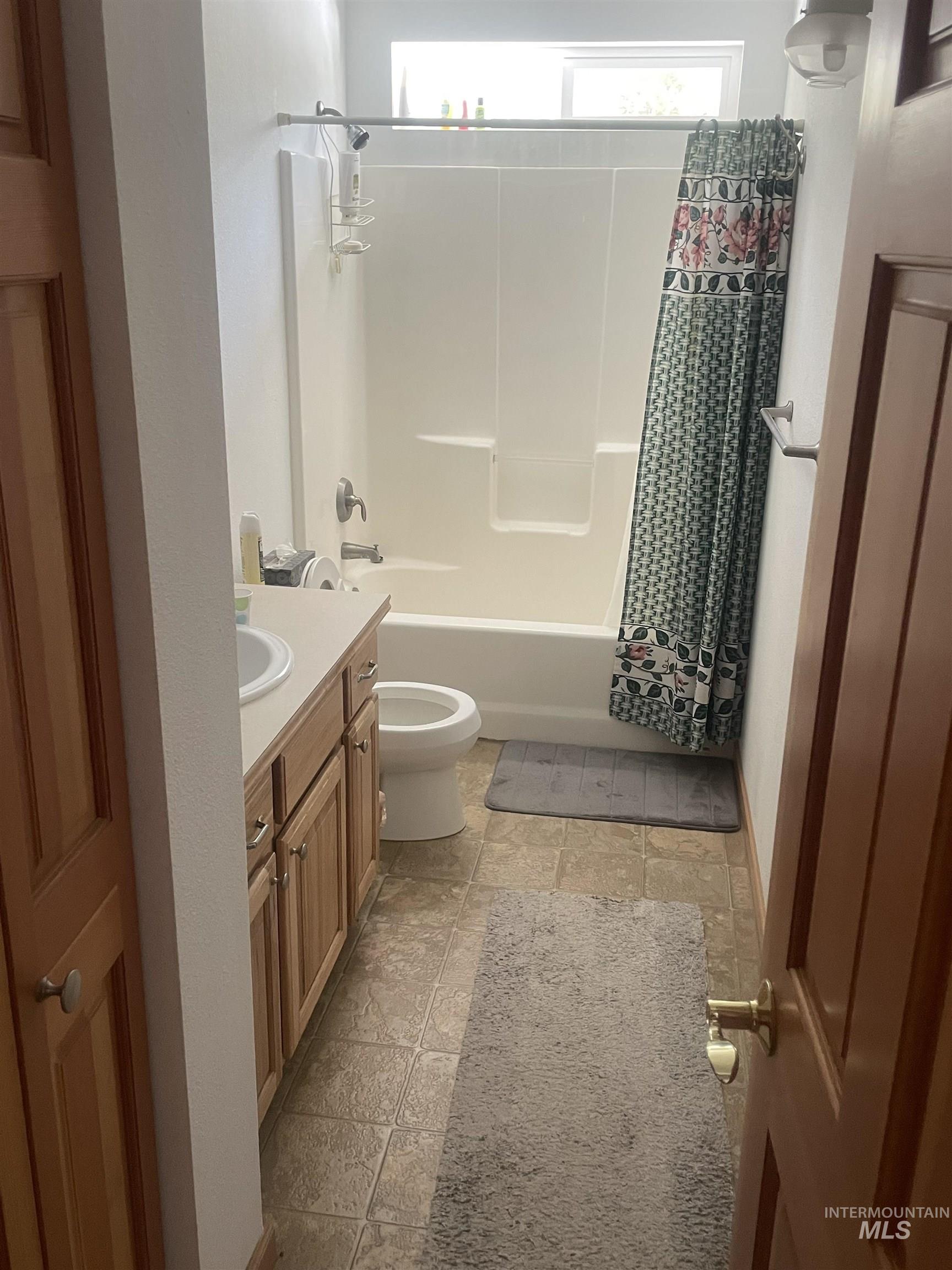 17567 Edwardsburg Road Yellow Pine, ID 83677 - Photo 10 of 11 Full bathroom featuring a single vanity with wood-finish cabinetry, a white porcelain sink, and a combination shower-tub unit