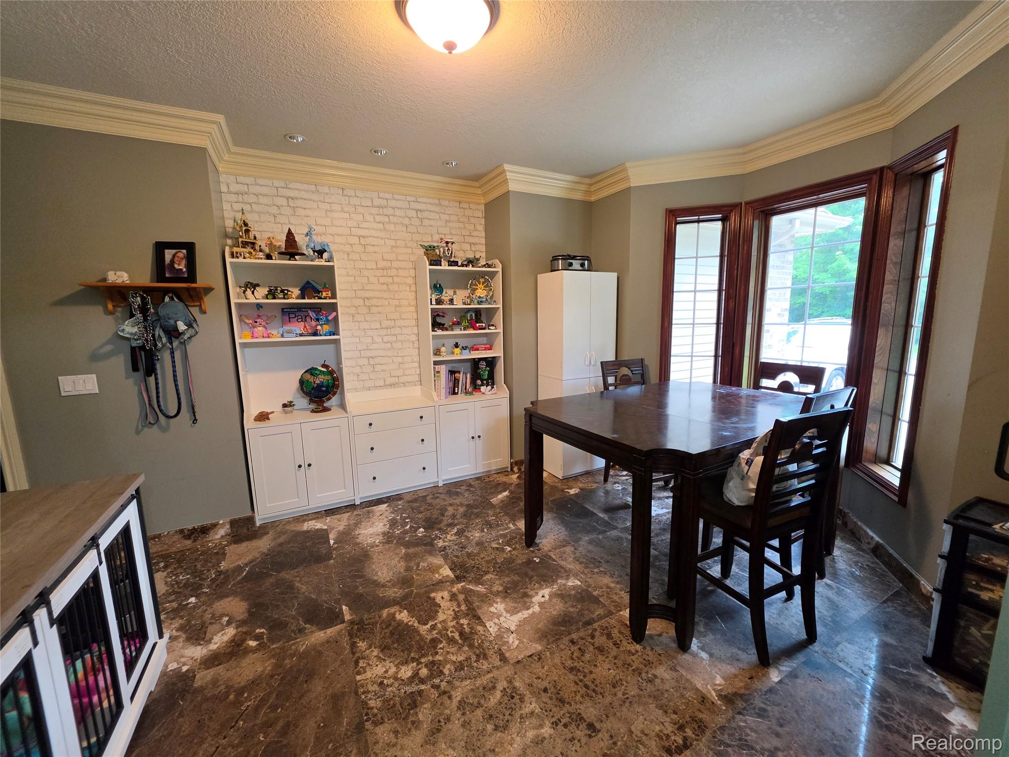 5150 West Carpenter Road Flint, MI 48504 - Photo 14 of 33 Spacious room featuring dark patterned tile flooring, a prominent bay window with dark wood trim, and extensive crown molding