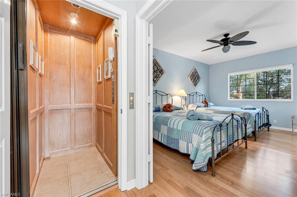 5735 Persimmon Way Naples, FL 34110 - Photo 14 of 49 Bedroom with ceiling fan, elevator, and light hardwood / wood-style flooring