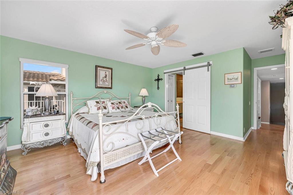 5735 Persimmon Way Naples, FL 34110 - Photo 19 of 49 Bedroom featuring ceiling fan, a barn door, and light hardwood / wood-style floors