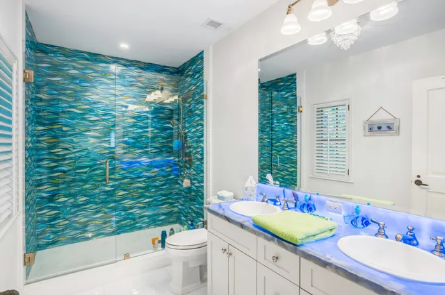 a bathroom with a double vanity sink a toilet and shower