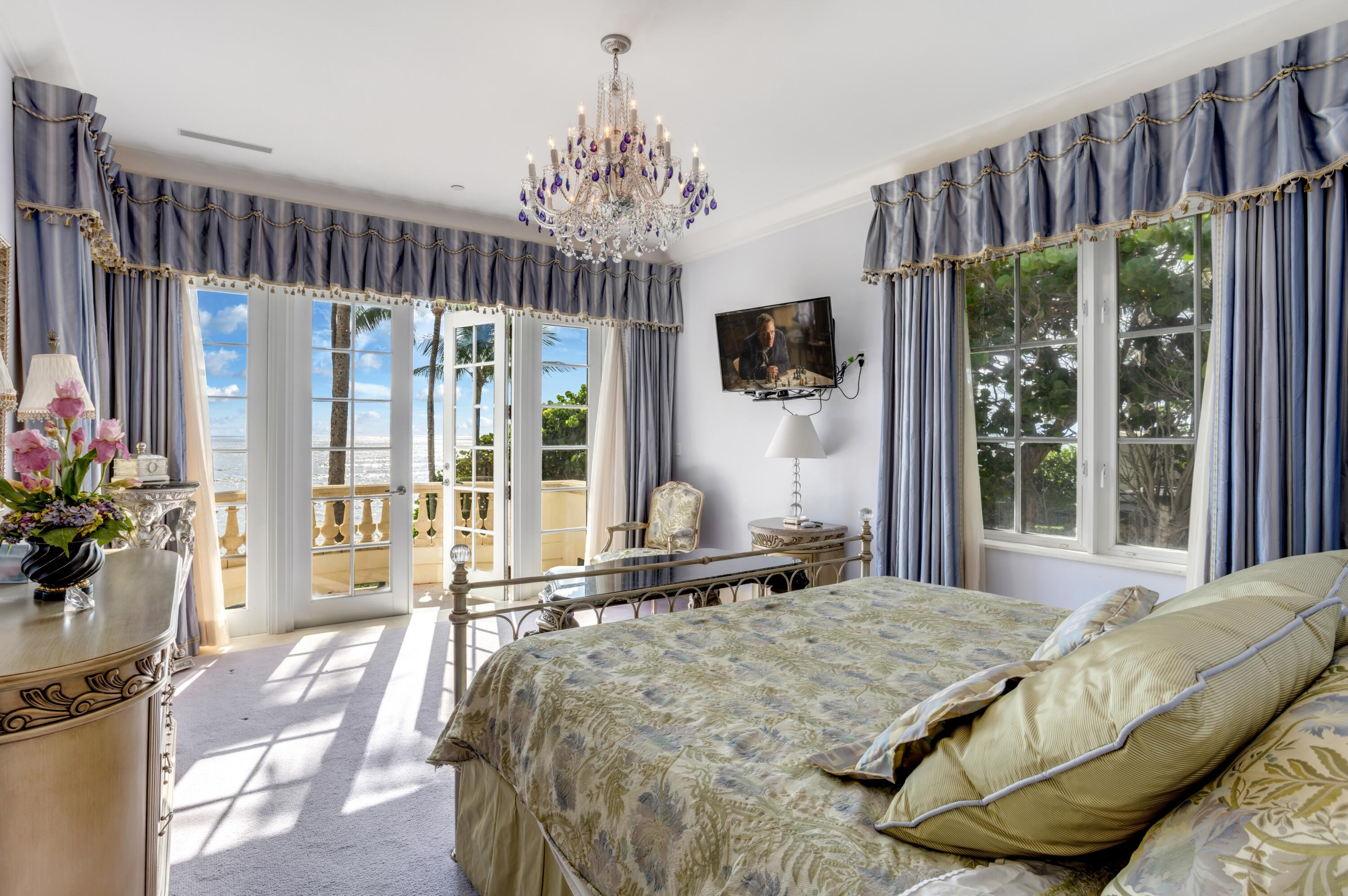 6133 North Ocean Boulevard Ocean Ridge, FL 33435 - Photo 36 of 64 a bed sitting in a bedroom next to a large window with a flat screen tv