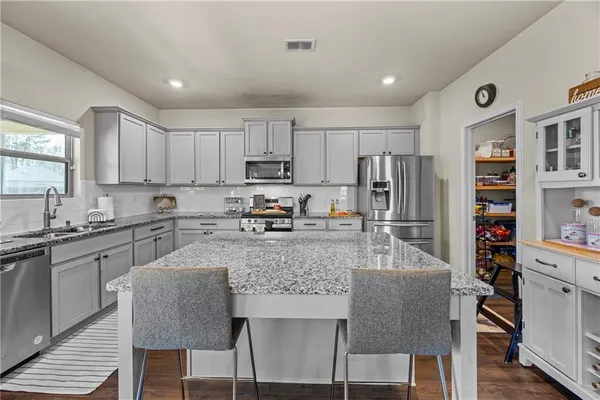 a kitchen with stainless steel appliances granite countertop a stove top oven a sink dishwasher and a refrigerator with the cabinets