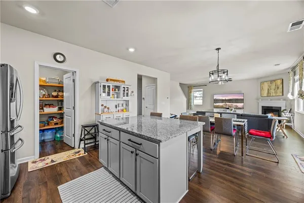 a kitchen with stainless steel appliances granite countertop a refrigerator a sink dishwasher a stove and white countertops with wooden floor