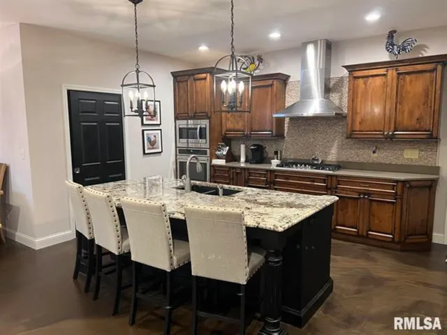 a kitchen with stainless steel appliances granite countertop a kitchen island a stove a table and chairs