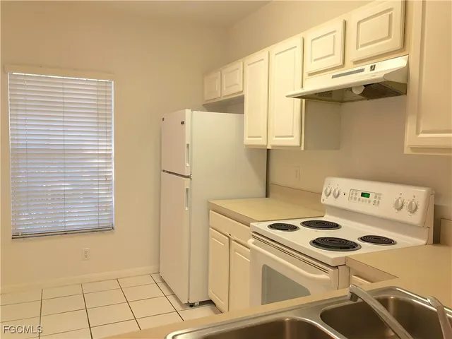 a kitchen with a stove a refrigerator and a more cabinets