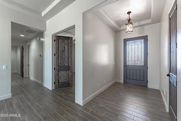 an empty room with wooden floor chandelier and entryway