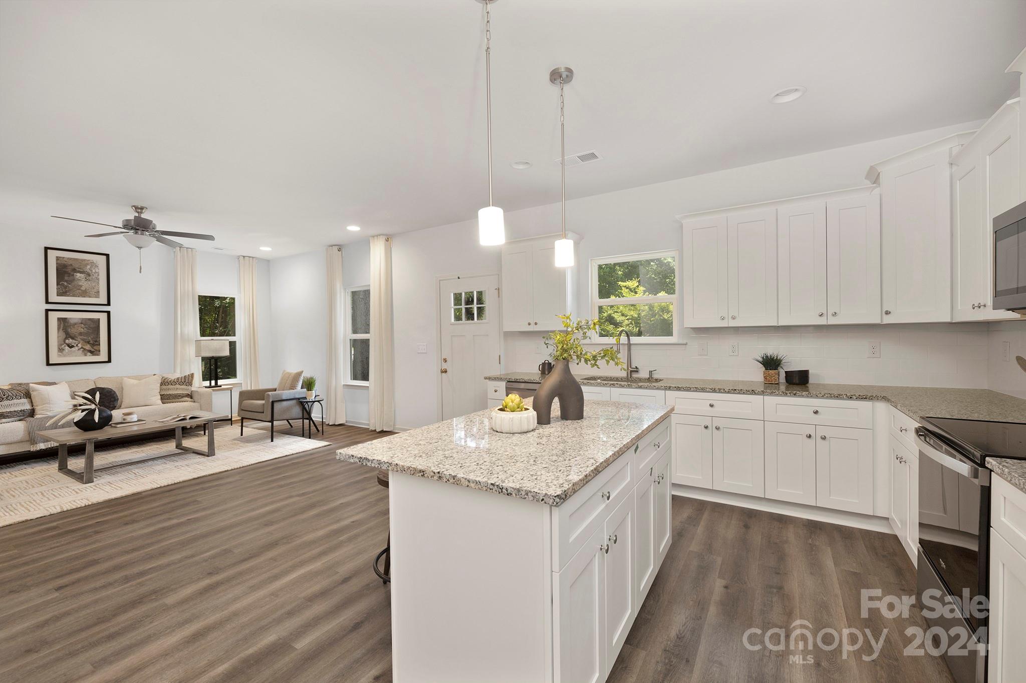 310 Morningside Road Charlotte, NC 28214 - Photo 5 of 23 a kitchen with granite countertop a sink stove and white cabinets with wooden floor
