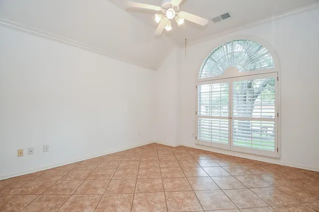 en empty room with windows and chandelier fan