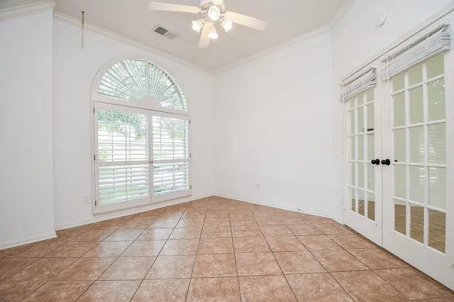 an empty room with chandelier fan and windows