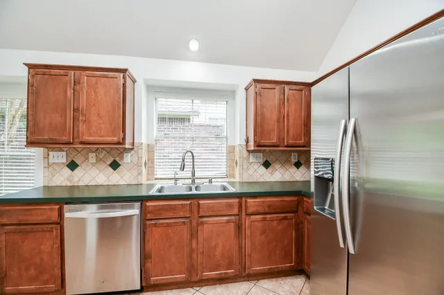 a kitchen with stainless steel appliances granite countertop a refrigerator and a sink