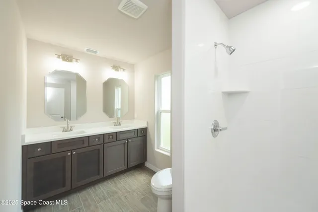 a bathroom with a double vanity sink toilet and a mirror