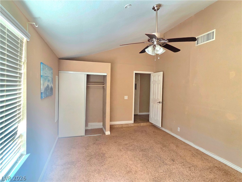 3648 Bronco Road Las Vegas, NV 89103 - Photo 7 of 24 A comfortable bedroom with a vaulted ceiling features a window with blinds and a closet with sliding doors.