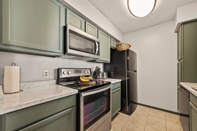 a kitchen with stainless steel appliances granite countertop a refrigerator a stove and a sink