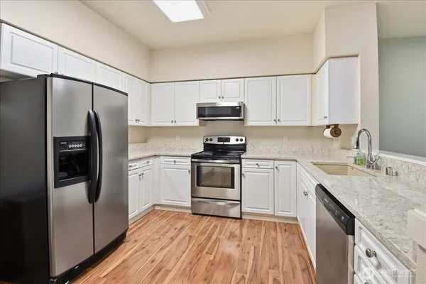 a kitchen with granite countertop a refrigerator stove and sink with wooden floor