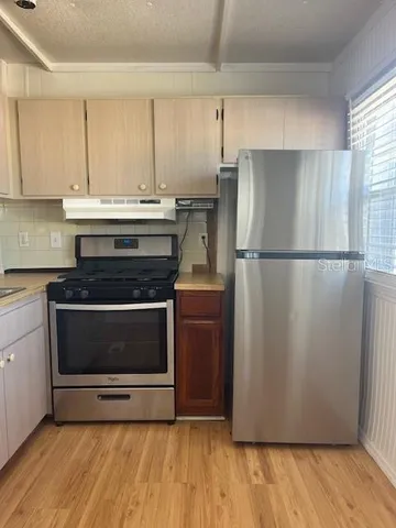 a kitchen with stainless steel appliances wooden cabinets and a wooden floor