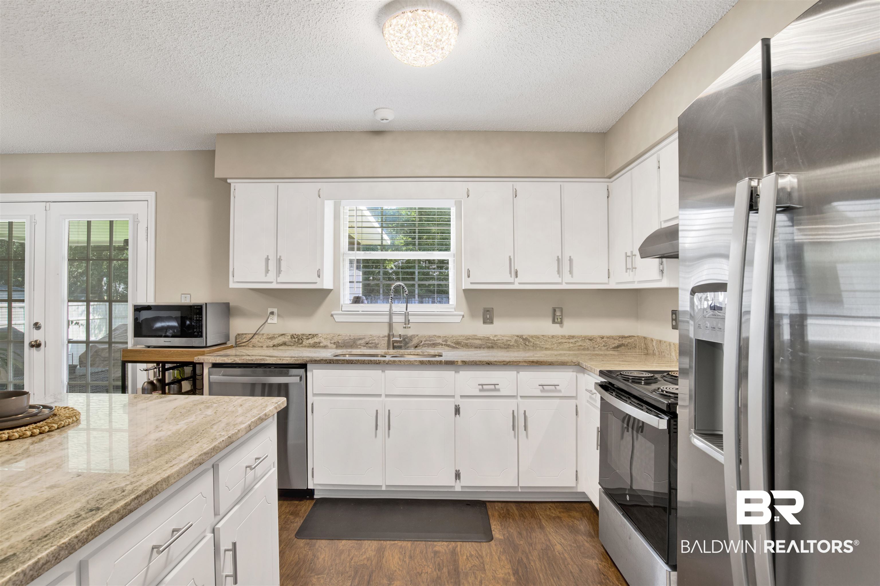 6281 Woodside Drive Theodore, AL 36582 - Photo 6 of 17 Kitchen with appliances with stainless steel finishes, a textured ceiling, light stone counters, french doors, and white cabinets
