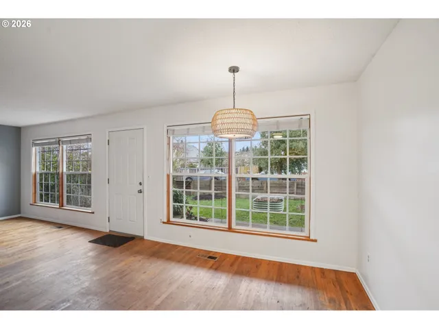 a view of an empty room with wooden floor fan and a window