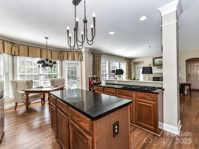 a kitchen with stainless steel appliances granite countertop a kitchen island a stove a table and chairs