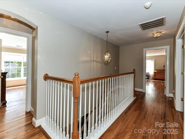 a view of a hallway with wooden floor and windows