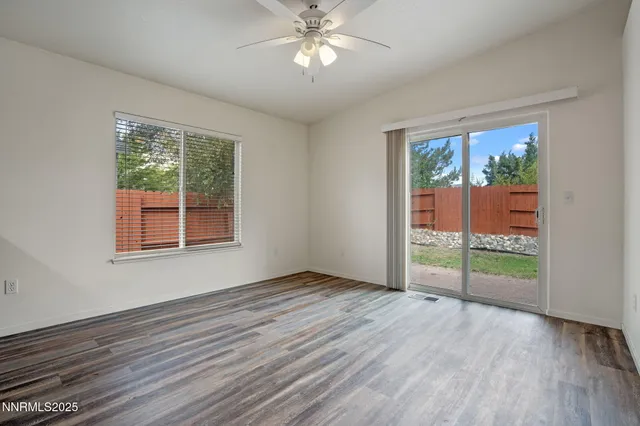 an empty room with wooden floor fan and windows