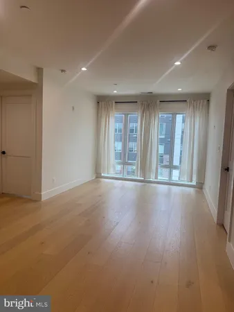 a view of an empty room with wooden floor and fan