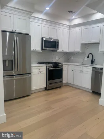 a kitchen with granite countertop a refrigerator and a stove top oven