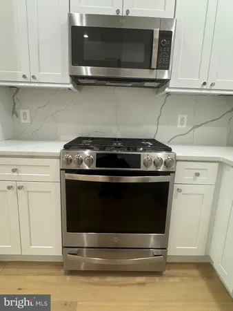 a stove top oven sitting inside of a kitchen and white cabinets