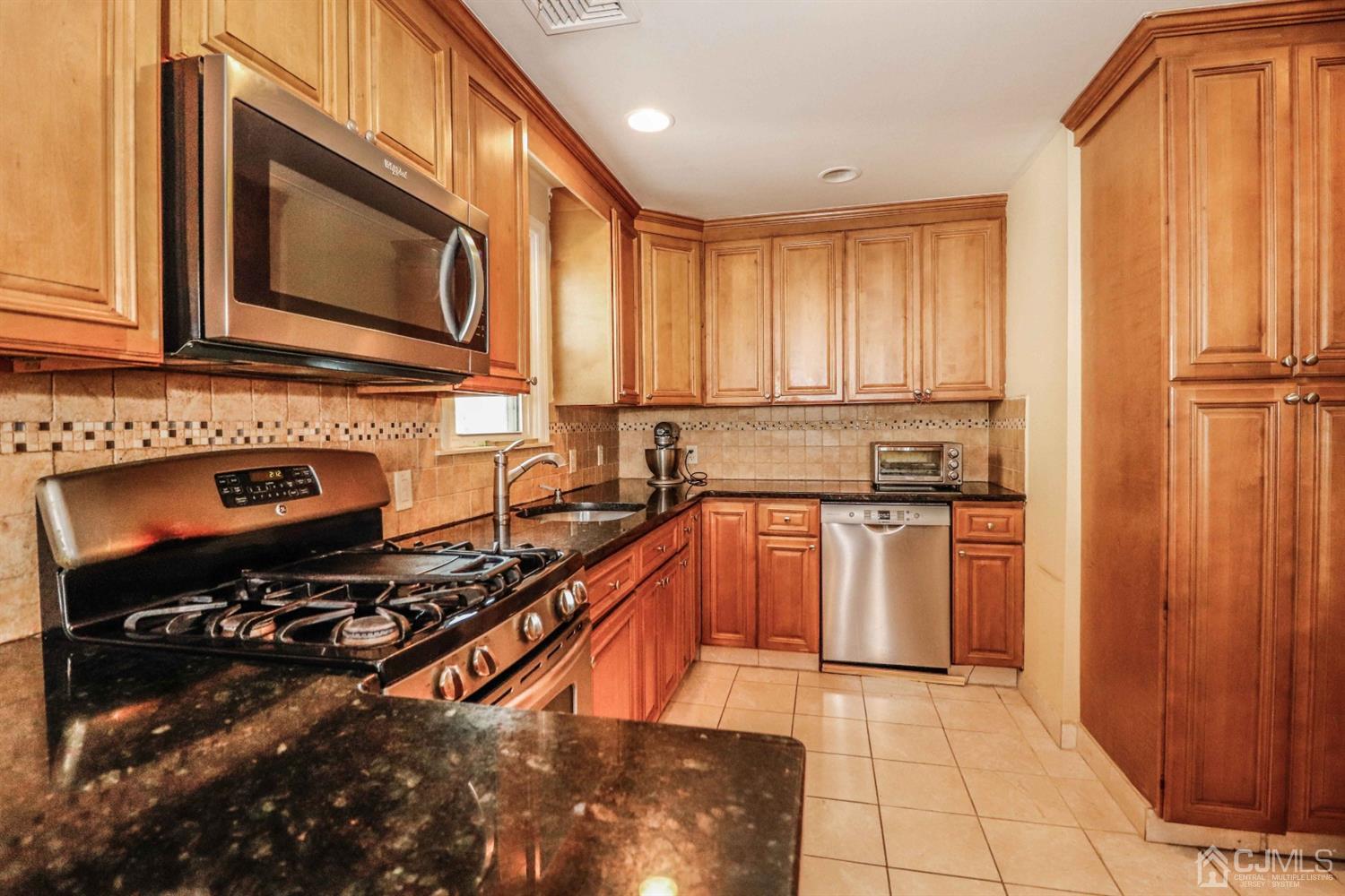 166 Brower Avenue Edison, NJ 08837 - Photo 19 of 48 a kitchen with stainless steel appliances a stove a sink and a microwave