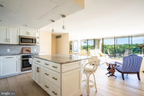 a kitchen with kitchen island granite countertop a stove a sink a dining table and chairs with wooden floor