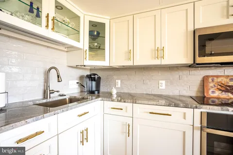 a kitchen with granite countertop a sink a stove and cabinets