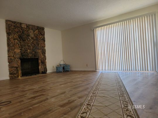 732 West Alene Avenue Ridgecrest, CA 93555 - Photo 21 of 38 an empty room with wooden floor fireplace and windows