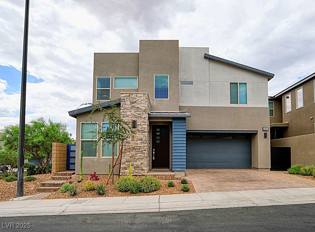Modern home with a standing seam roof, stucco siding, a metal roof, and decorative driveway