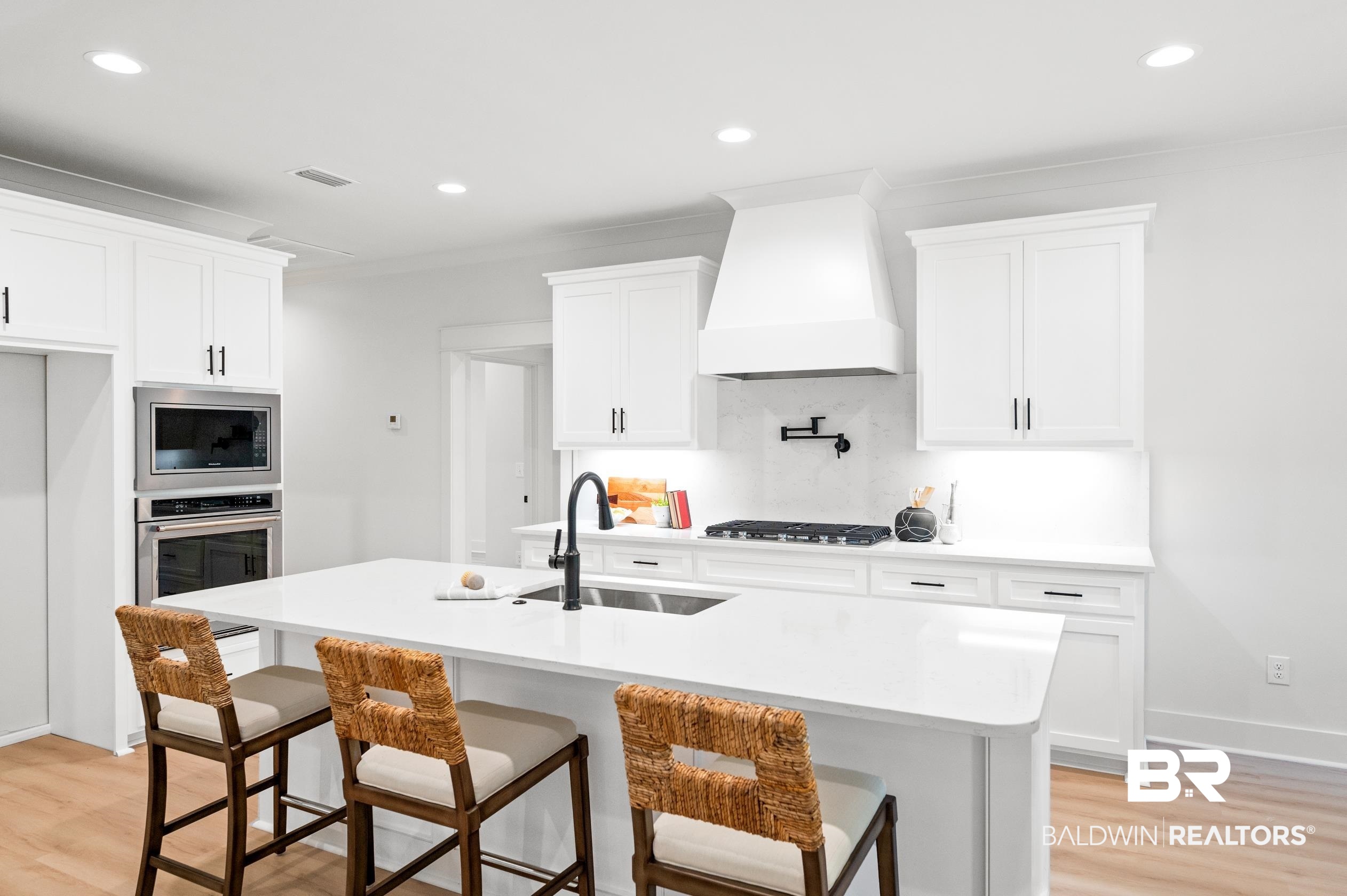 28889 Canal Road Orange Beach, AL 36561 - Photo 10 of 55 Kitchen featuring a center island with sink, white cabinets, sink, and premium range hood