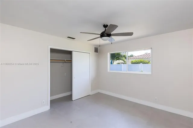 an empty room with a window and a ceiling fan